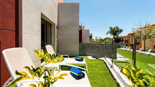 Aurinkotuoleja sinisillä pyyhkeillä nurmikolla lähellä taloa. (Tekoälyn luoma teksti)