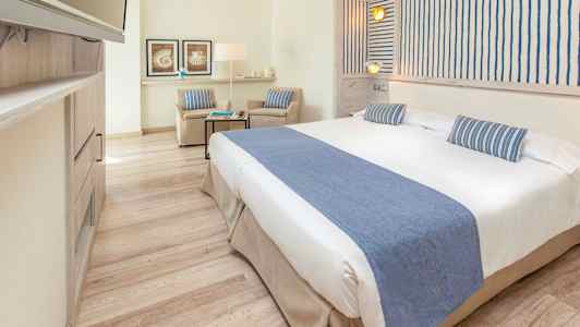 Kirkas hotellihuone, jossa on leveä sänky ja sinisiä koristeita. (Tekoälyn luoma teksti)