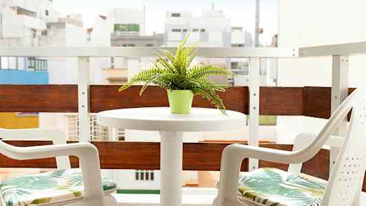 Parveke, jossa pöytä ja kaksi tuolia, pöydällä vihreä ruukkukasvi. (Tekoälyn luoma teksti)