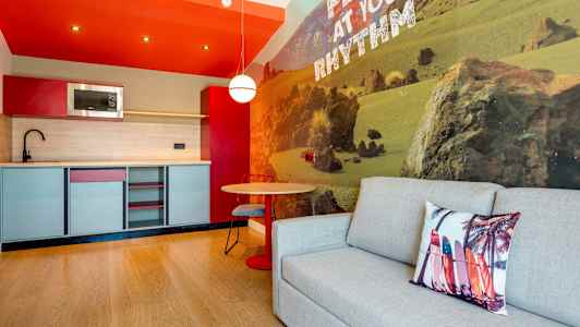 Moderni keittiö, jossa on istuinryhmä ja sohva, seinällä luontoteema. (Tekoälyn luoma teksti)