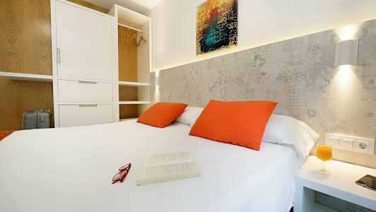 Makuuhuone, jossa valkoinen parisänky, oranssit tyynyt ja avoin vaatekaappi. (Tekoälyn luoma teksti)