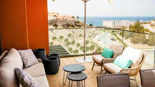 Terassi, jossa on istuinalue varjon alla ja näkymä merelle. (Tekoälyn luoma teksti)