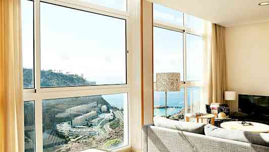 Olohuone, jossa suuret ikkunat ja näkymä merelle ja kalliolle. (Tekoälyn luoma teksti)