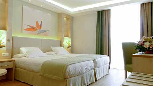 Hotellihuone, jossa on parivuode, koristeet ja ikkunat verhoineen. (Tekoälyn luoma teksti)