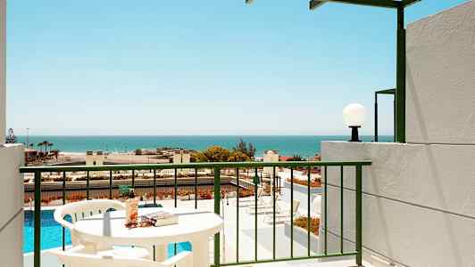 Parveke, josta näkymä uima-altaalle ja merelle, näkyvissä pöytiä ja tuoleja. (Tekoälyn luoma teksti)