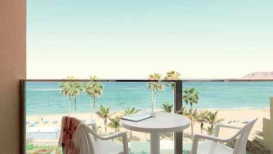 Parveke, josta näkymä rannalle ja merelle, pöytä ja tuolit näkyvissä. (Tekoälyn luoma teksti)