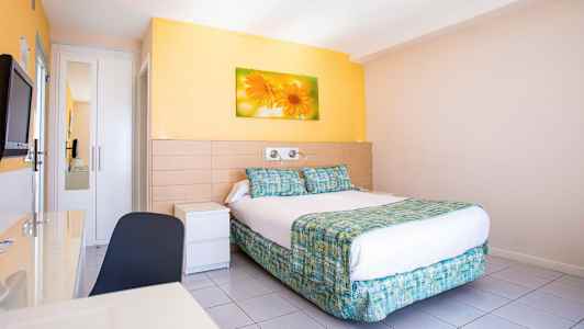 Hotellihuone, jossa on parivuode, seinämaalaus kukista sängyn yläpuolella ja vaaleat seinät. (Tekoälyn luoma teksti)