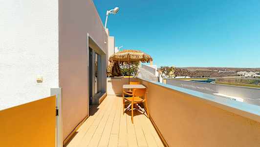 Parveke, jossa on pöytä, tuolit ja varjo näkymällä ympäristöön. (Tekoälyn luoma teksti)