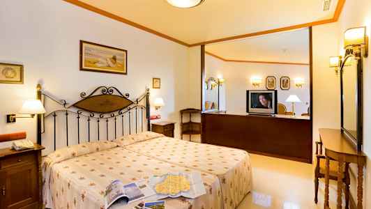 Hotellihuone, jossa on parivuode, yöpöytä ja televisio tason päällä. (Tekoälyn luoma teksti)