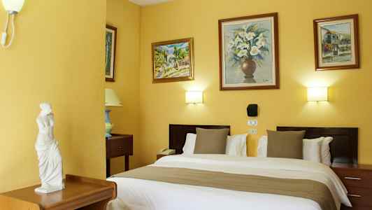 Hotellihuone, jossa on parisänky, koristellut seinät maalauksilla ja pieni patsas huonekalulla. (Tekoälyn luoma teksti)