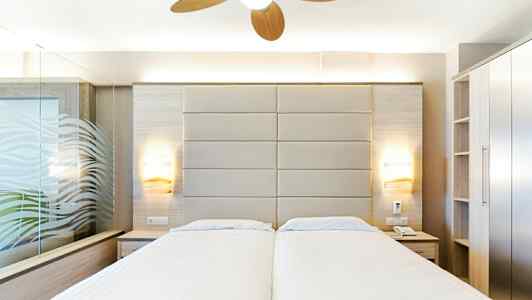 Hotellihuone, jossa kaksi erillistä vuodetta, moderni sisustus ja kattotuuletin. (Tekoälyn luoma teksti)