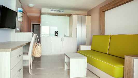 Moderni hotellihuone, jossa sohva, kirjoituspöytä ja keittokomero. (Tekoälyn luoma teksti)