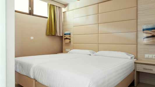 Hotellihuone, jossa on kaksi sänkyä ja beige seinäpaneeli. (Tekoälyn luoma teksti)