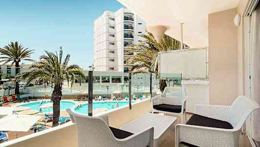 Näkymä terassilta, jossa on istuinryhmä, uima-allas ja ympäröivät rakennukset. (Tekoälyn luoma teksti)