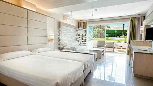 Hotellihuone, jossa on kaksi sänkyä ja avautuminen puutarhaan. (Tekoälyn luoma teksti)