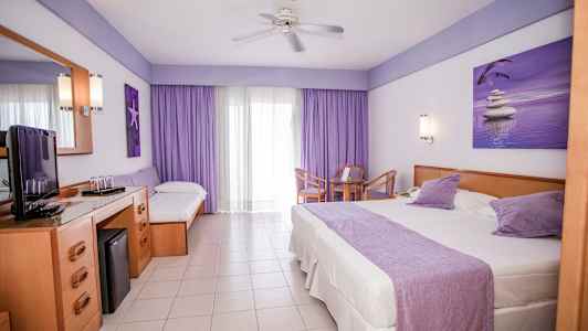 Hotellihuone, jossa on suuri sänky, yhden hengen sänky, pöytä tuoleineen ja TV-taso. (Tekoälyn luoma teksti)