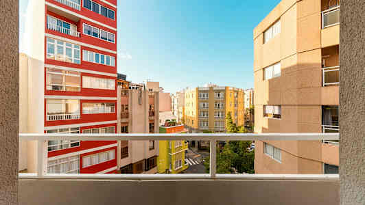 Näkymä parvekkeelta, jossa on useita rakennuksia ja sininen taivas taustalla. (Tekoälyn luoma teksti)