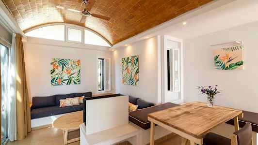 Sisustus, jossa on puupöytä, sohva ja seinäkoristeet kasviaiheilla. (Tekoälyn luoma teksti)