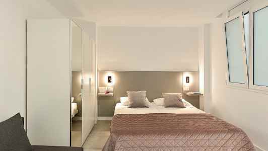 Hotellihuone, jossa parivuode, vaaleanpunainen päiväpeite ja vaatekaappi. (Tekoälyn luoma teksti)