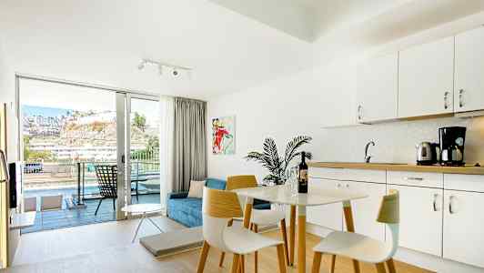 Valoisasti sisustettu hotellihuone, jossa keittiötila ja parveke näkymällä. (Tekoälyn luoma teksti)