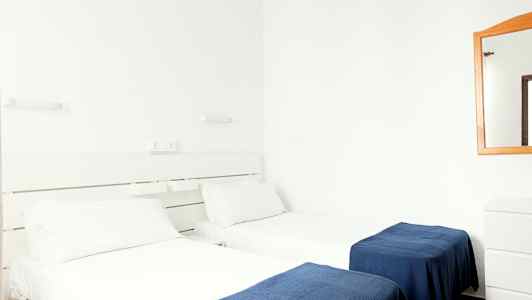 Kaksi yhden hengen sänkyä, joissa on valkoiset lakanat ja siniset peitot hotellihuoneessa. (Tekoälyn luoma teksti)