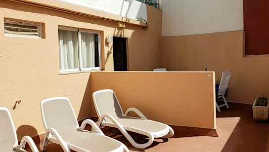 Terassi, jossa on aurinkotuoleja ja pöytä tuoleineen. (Tekoälyn luoma teksti)