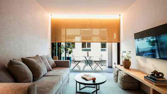 Olohuone, jossa sohva, sohvapöytä ja näkymä parvekkeelle. (Tekoälyn luoma teksti)