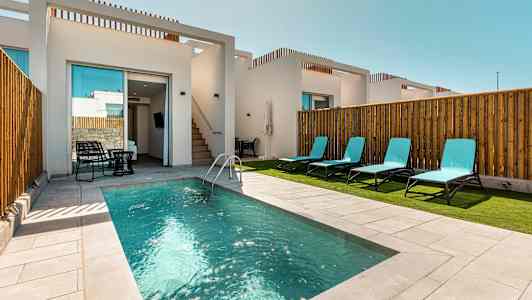 Viehättävä uima-allas valkoisen modernin rakennuksen edessä, ympärillä aurinkotuolit. (Tekoälyn luoma teksti)