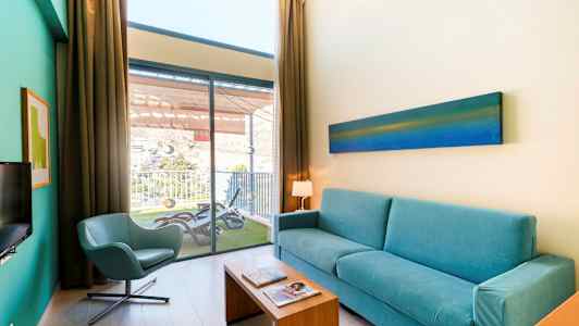 Olohuone, jossa on sininen sohva, tuoli ja näkymä parvekkeelle. (Tekoälyn luoma teksti)