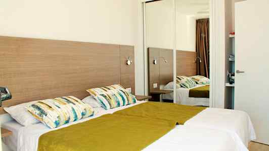 Kahden hengen huone, jossa kaksi erillistä sänkyä, peili ja puukalusteet. (Tekoälyn luoma teksti)