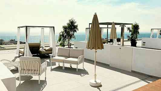 Terassi, jossa aurinkotuoleja, varjo ja näkymä merelle. (Tekoälyn luoma teksti)