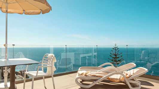 Terassi, jossa aurinkotuoleja, aurinkovarjo ja merinäköala. (Tekoälyn luoma teksti)