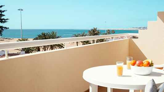 Parveke näköalalla merelle, pöytä hedelmäkulholla ja lasillinen mehua. (Tekoälyn luoma teksti)