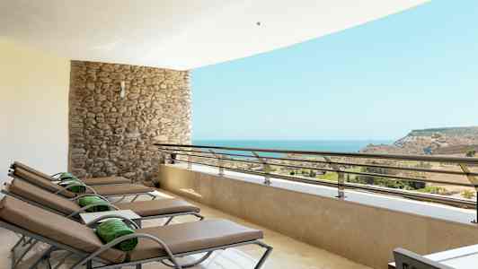 Terassi, jossa on aurinkotuoleja ja näkymä merelle. (Tekoälyn luoma teksti)