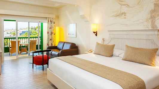 Hotellihuone, jossa on parisänky, oleskelutila ja parveke. (Tekoälyn luoma teksti)