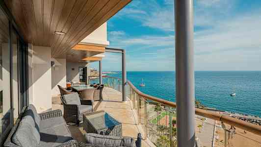 Parveke, jossa on istuimia ja näkymä merelle ja rannalle. (Tekoälyn luoma teksti)