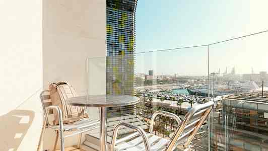 Parveke, jossa on kaksi tuolia ja pöytä, näkymä satamaan. (Tekoälyn luoma teksti)