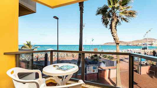 Näkymä parvekkeelta, jossa pöytä ja tuolit, merelle ja rannalle. (Tekoälyn luoma teksti)