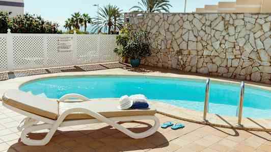 Ulkouima-allas, jossa aurinkotuoli ja pino pyyhkeitä ja hattu. (Tekoälyn luoma teksti)