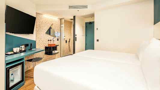 Hotellihuone, jossa sänky, työpöytä ja kylpyhuonealue. (Tekoälyn luoma teksti)