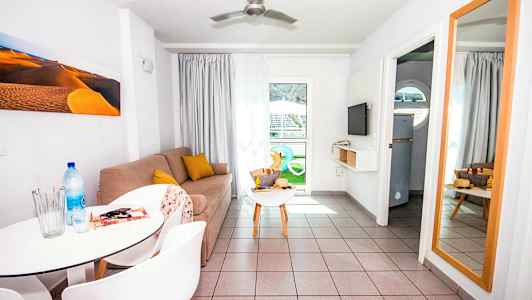 Olohuone, jossa on sohva, sivupöytä, peili ja ruokapöytä tuoleineen. (Tekoälyn luoma teksti)