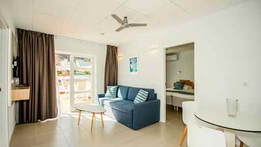 Olohuone, jossa on sohva, pöytä, ruokailutila ja ovi makuuhuoneeseen. (Tekoälyn luoma teksti)