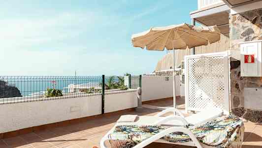 Aurinkotuoli ja varjo terassilla, näköala merelle. (Tekoälyn luoma teksti)