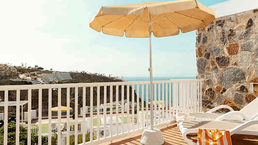 Näkymä terassilta aurinkotuolin, varjon ja taustalla olevan meren kera. (Tekoälyn luoma teksti)