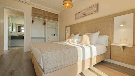 Vaalea makuuhuone, jossa on parivuode, vaatekaappi ja avoin kylpyhuone. (Tekoälyn luoma teksti)