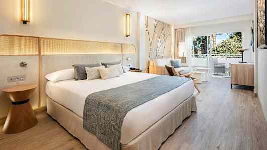 Hotellihuone, jossa parivuode, oleskelutila ja parveke näkymällä. (Tekoälyn luoma teksti)