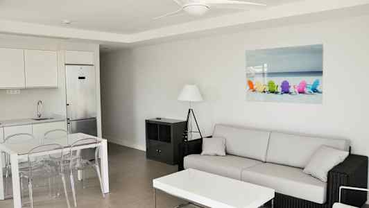 Modernisti sisustettu olohuone, jossa sohva, sohvapöytä, ruokapöytä ja keittiö. (Tekoälyn luoma teksti)