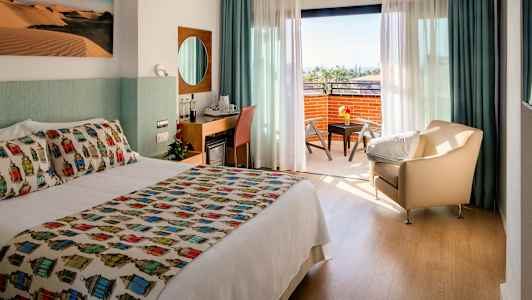 Hotellihuone, jossa on parivuode, oleskelualue ja parveke näkymällä. (Tekoälyn luoma teksti)