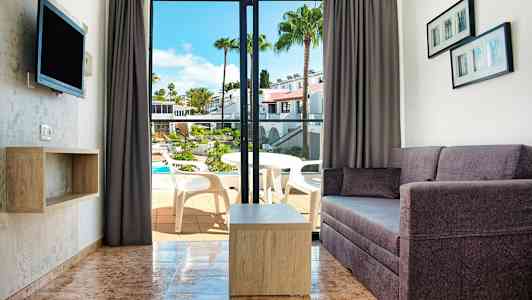 Näköala olohuoneeseen, jossa sohva ja pöytä, sekä avaus parvekkeelle, josta on näkymä uima-altaalle. (Tekoälyn luoma teksti)