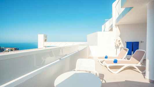 Terassi, jossa aurinkotuoleja ja upea näkymä merelle. (Tekoälyn luoma teksti)